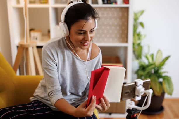 A person wearing headphones and holding a book Description automatically generated